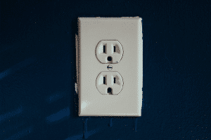 An electrical outlet on a blue wall, an important piece in electrical safety.