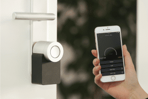 Smart home lock with person holding up phone with accompanying app.