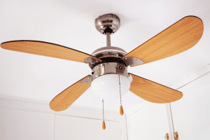 Ceiling fan in a white room with wooden blades and light bulbs that keep burning out.