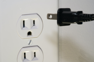 Unplugging a black plug out of a socket to save on electric bill.