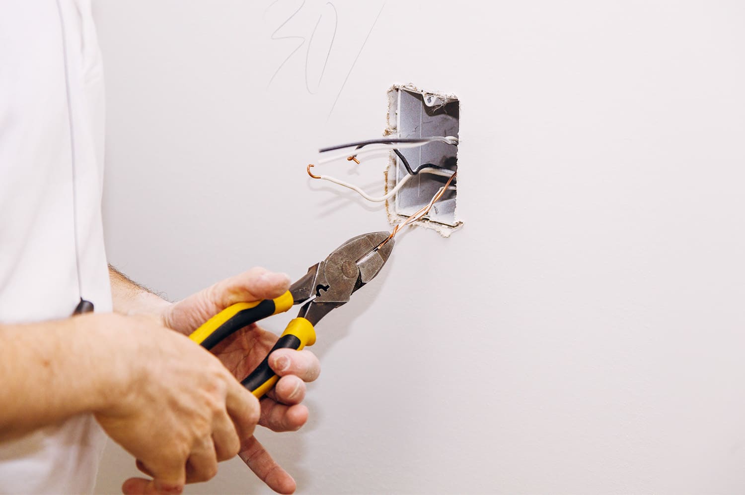 An anonymous person working on electrical repairs in their home.