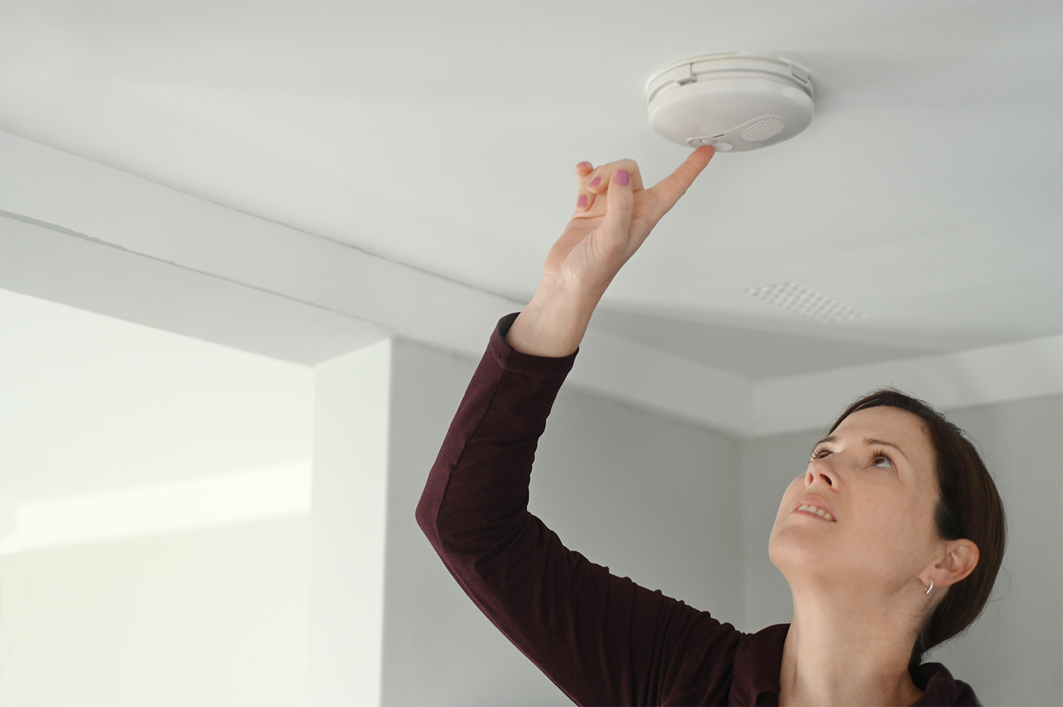 A woman testing a smoke detector in her Tennessee home to see if she needs to replace it.